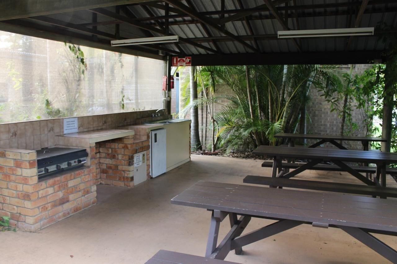Een barbecue buiten met een bakstenen grill, een spoelbak en een picknicktafel.