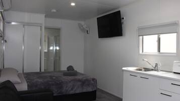 A compact bedroom with a bed, bedside table, and a TV mounted on the wall.