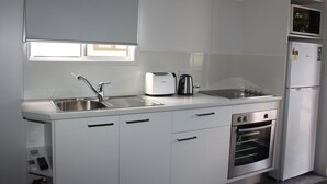 Una cocina moderna con un lavaplatos de acero inoxidable, un tostador, un hervidor, un microondas y un horno empotrado.