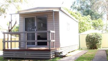 A small, single-story mobile home with a porch and a sliding door.