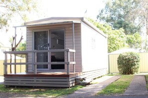 A small, single-story mobile home with a porch and a sliding door. - Huntsville Caravan Park (Maryborough)