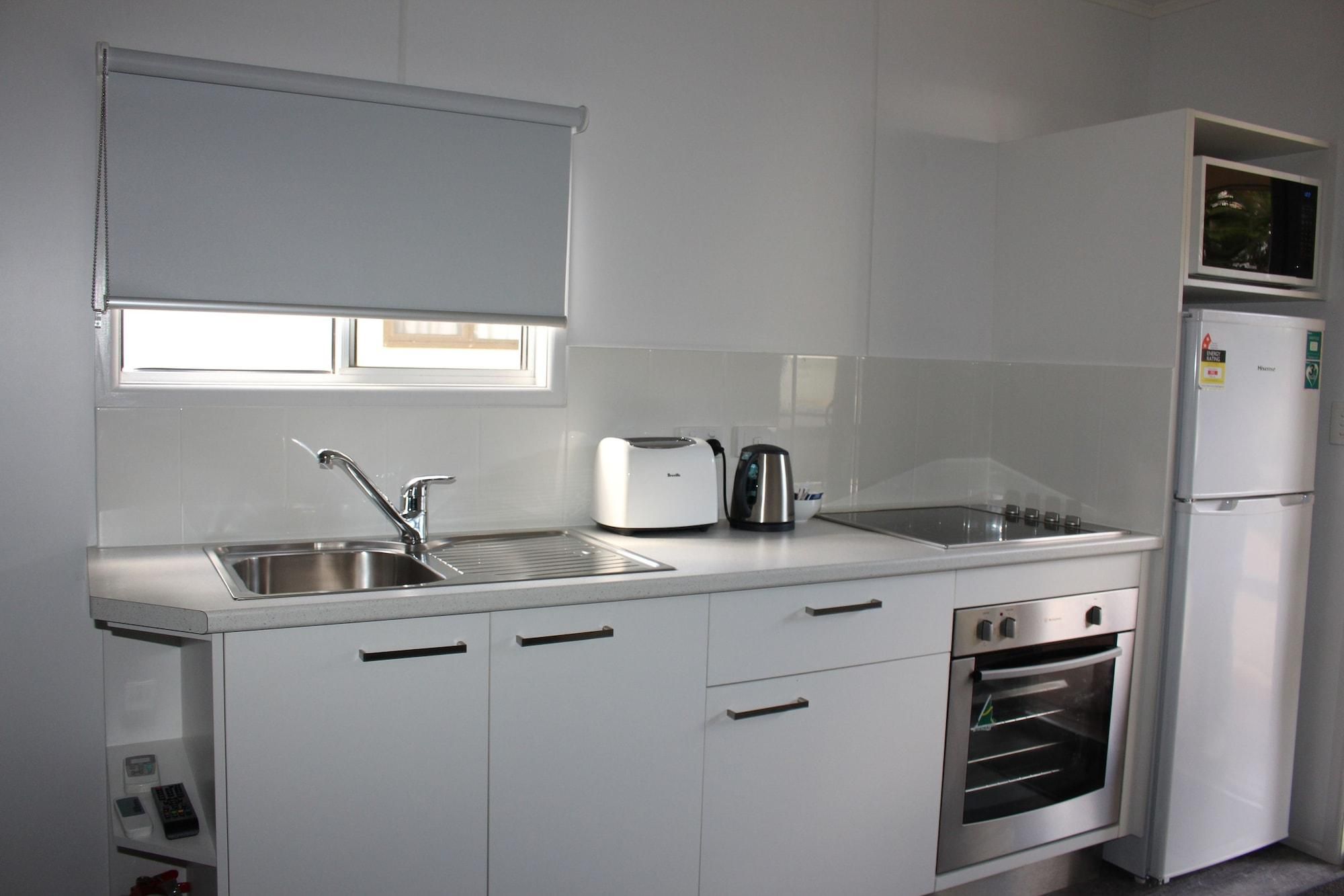 Een moderne keuken met een roestvrijstalen spoelbak, een broodrooster, een waterkoker, een magnetron en een inbouwoven.