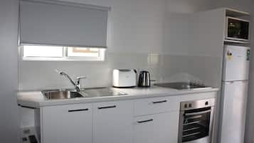 Een moderne keuken met een roestvrijstalen spoelbak, een broodrooster, een waterkoker, een magnetron en een inbouwoven.