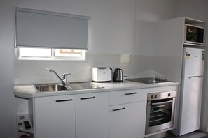 Una cocina moderna con un lavaplatos de acero inoxidable, un tostador, un hervidor, un microondas y un horno empotrado.
