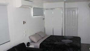 Un dormitorio con cama, una silla, armario y una puerta.