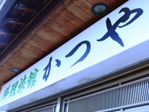 Un letrero con caracteres japoneses, presumiblemente indicando el nombre de un negocio o establecimiento.