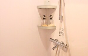 Un baño con ducha, grifo y dispensador de jabón.