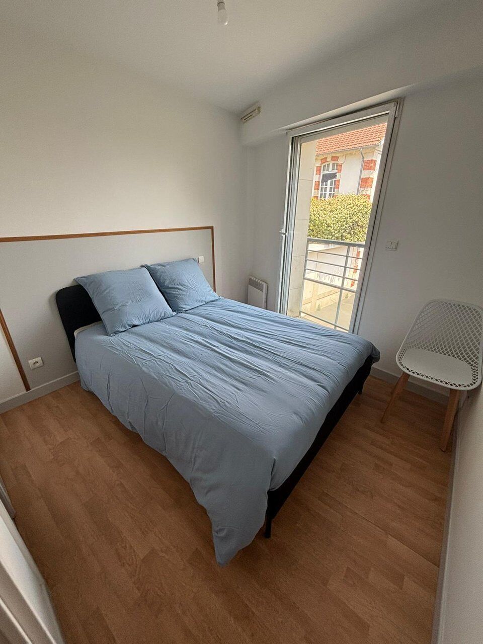 A bedroom with a bed, a chair, a window, and a door.