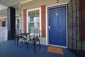 A blue door with the number 3, a porch with a table and chairs, and a brick pillar.