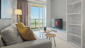 A modern living room with a sofa, a TV, a small table, and a balcony with a view. - Ardin by Kozystay - MERR (Surabaya)