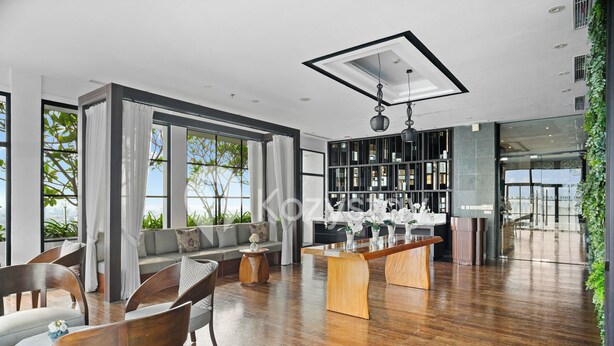A modern living room with a wooden floor, a sofa, chairs, a coffee table, and a bookshelf. - Ardin by Kozystay - MERR (Surabaya)
