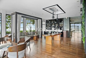 A modern living room with a wooden floor, a sofa, chairs, a coffee table, and a bookshelf. - Ardin by Kozystay - MERR (Surabaya)