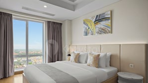A modern hotel room with a large bed, a view of the city, and a marble side table. - Ardin by Kozystay - MERR (Surabaya)