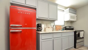 A kitchen with a red Galanz refrigerator, grey cabinets, a coffee maker, and a microwave. - SuperValue Suite #5 @ East End Revitalized (Houston)