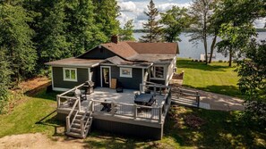 Ein zweistöckiges Haus mit Terrasse, Grill und Seeblick.