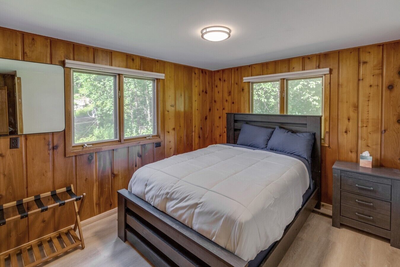 Ein Schlafzimmer mit einem Bett, zwei Fenstern, einem Nachttisch und einer Bank.