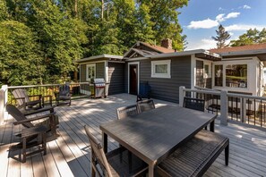 A deck with outdoor furniture, a grill, and a view of the surrounding forest. - Rustic Wilson Bay Cabin on Gull Lake,  Beach & Dock (Nisswa)