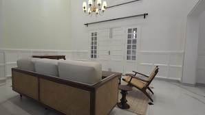 A room with a sofa, a chair, a table, a chandelier, and a door with glass panels.