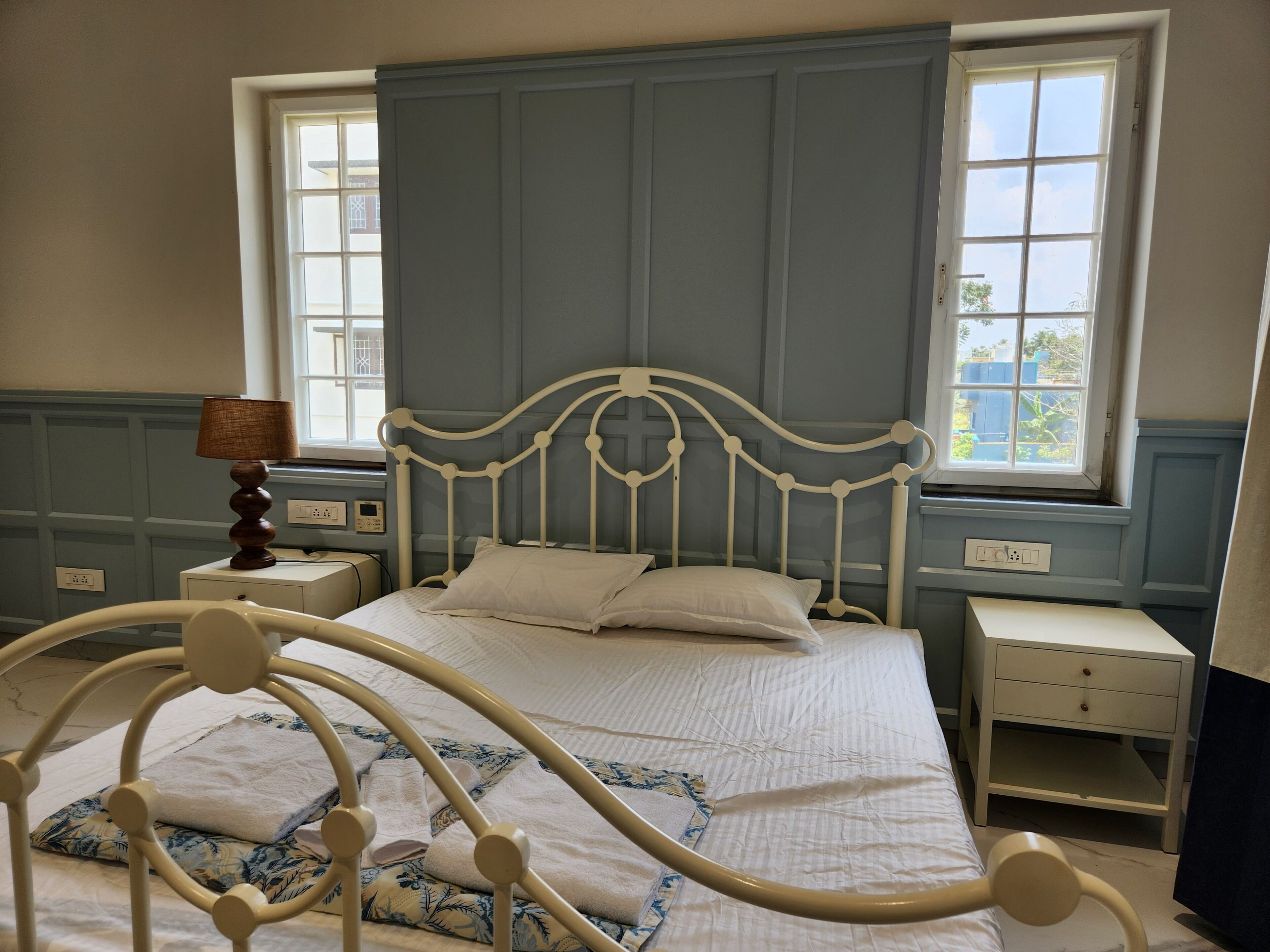 A bed with a headboard, a bedside table, a lamp, and a window with a view.
