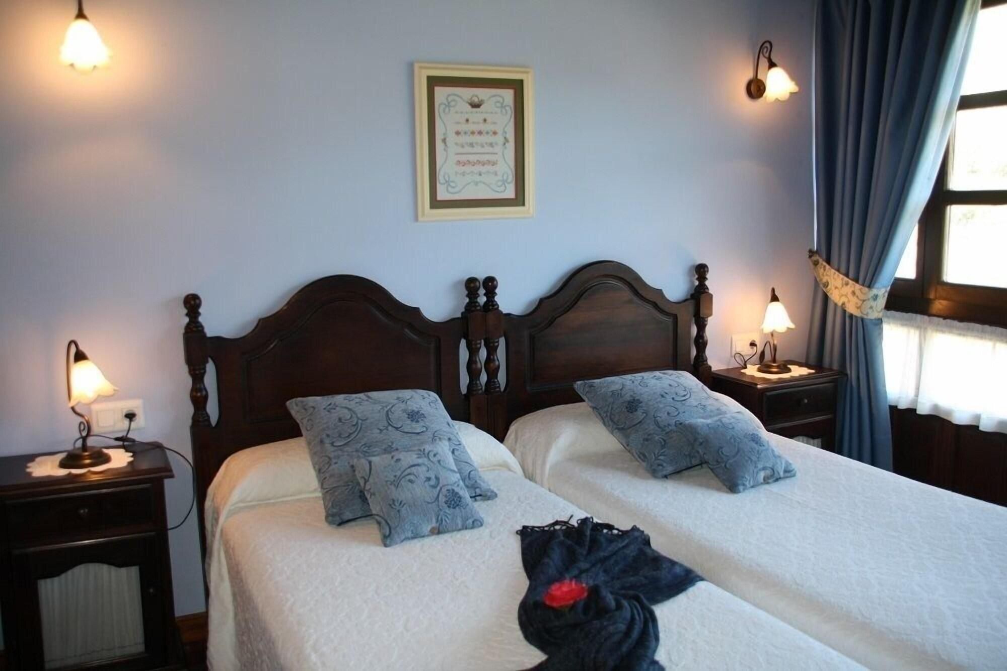 A double bed with a headboard, two bedside tables with lamps, a framed certificate on the wall, and a window with curtains.