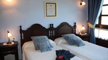 A double bed with a headboard, two bedside tables with lamps, a framed certificate on the wall, and a window with curtains.