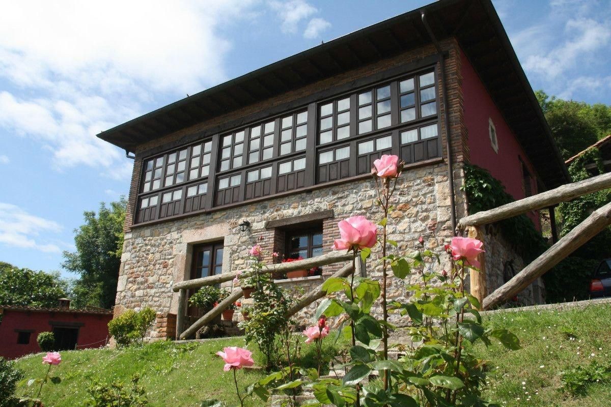 A stone building with a red facade, multiple windows, and a wooden staircase.