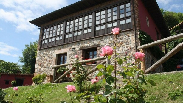 A stone building with a red facade, multiple windows, and a wooden staircase.