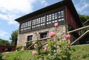 Un edificio de piedra con fachada roja, varias ventanas y una escalera de madera.
