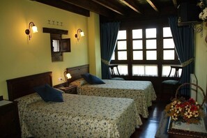 A room with two beds, a wooden ceiling, a window with curtains, and a wall-mounted light fixture. - Casa Rural El Trechal (Pilona)