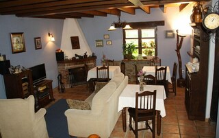 Una sala de estar acogedora con chimenea, un comedor con mesa y sillas, y una cocina con un reloj en la pared.