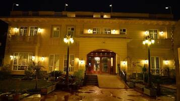 Fachada de hotel con un arco imponente, varias ventanas e iluminación exterior.