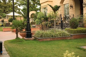 Ein gepflegter Garten mit einem Weg, der zu einem Gebäude mit Bogenfenstern und einer Treppe führt.