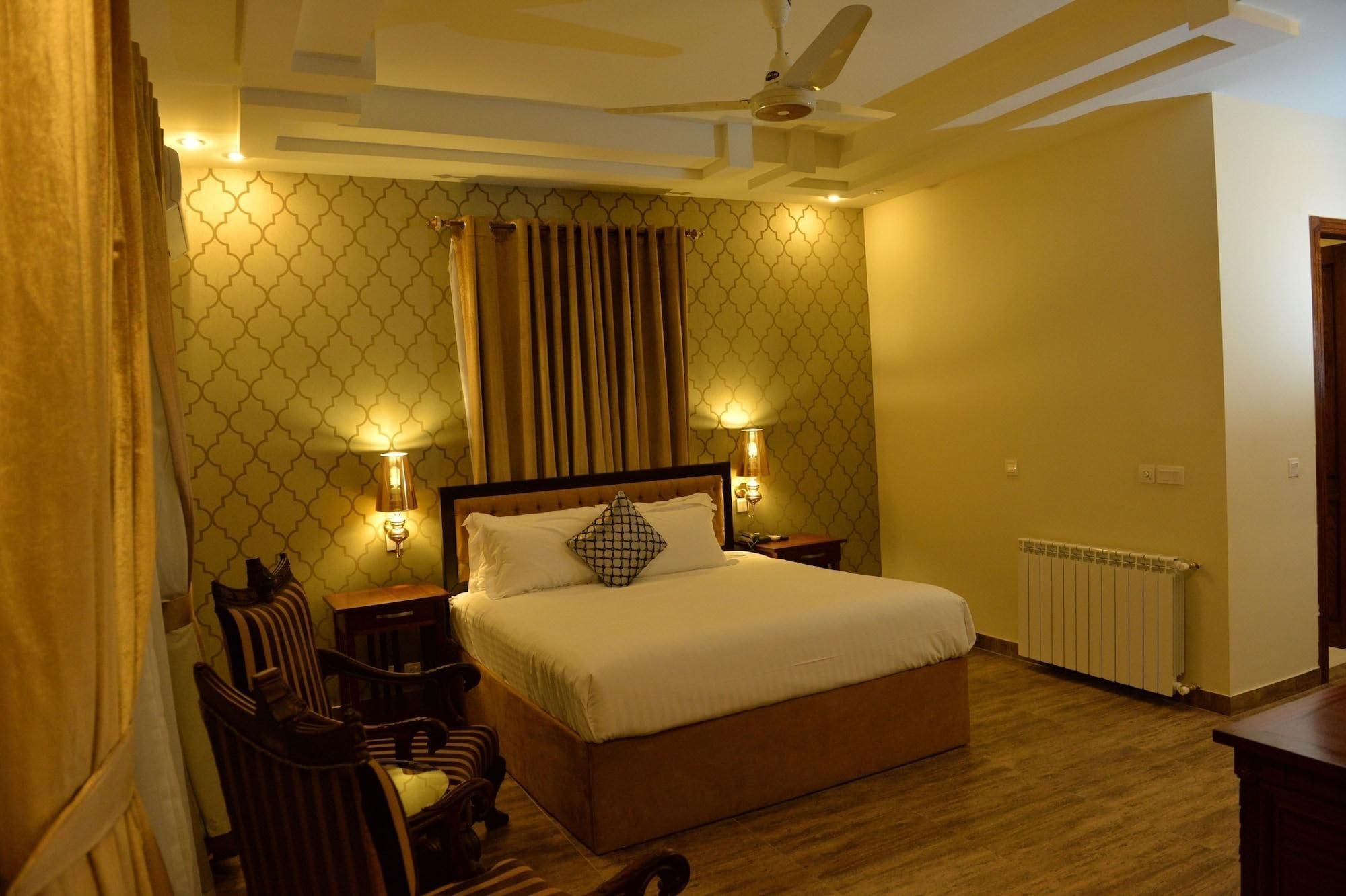 A bedroom with a bed, two bedside lamps, a ceiling fan, a radiator, and a patterned wall.
