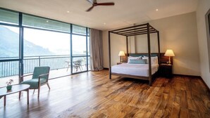 Una habitación con cama con dosel, dos lámparas de noche, una mesa de comedor con sillas y un balcón con vistas a las montañas.