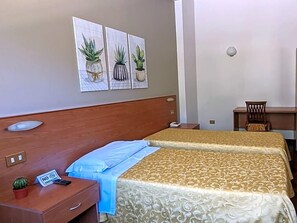 A hotel room with two beds, a desk, a chair, a small plant, and a 'No Smoking' sign. - Hotel Del Sole (Sora)