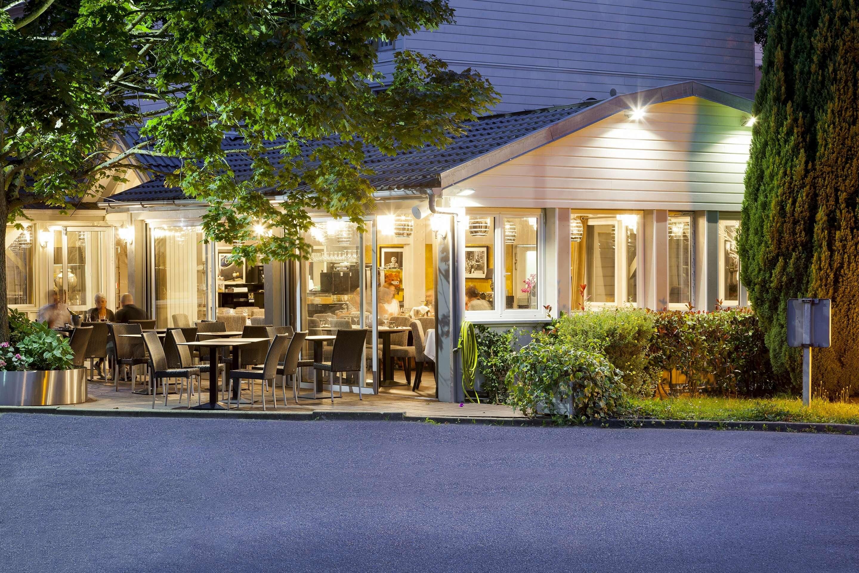 A restaurant with outdoor seating, a covered patio, and a well-lit entrance.
