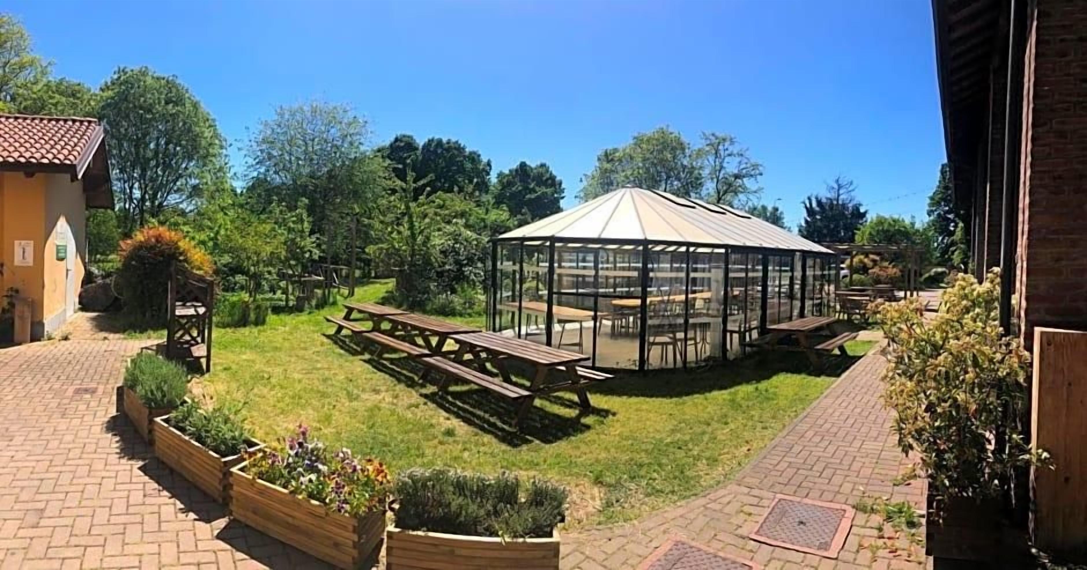 A gazebo with a glass roof, picnic tables, and a brick pathway.