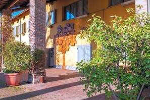 A building with a brick facade, a yellow wall with a decorative pattern, and a door with a sign above it. - Cascina Bellaria (Milan)
