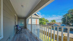 A covered porch with a table and chairs, a view of a residential street, and a clear blue sky. - Super Value Suite #6 - *4 km from FIFA Fan Fest* (Houston)