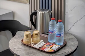 A tray with coffee cups, a kettle, bottled water, and snacks on a round table. - Down Town Hotel Aqaba (Aqaba)