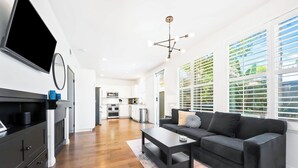 Un salon moderne avec un canapé noir, une table basse et un téléviseur.
