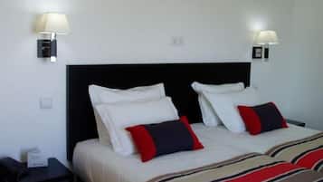 A hotel room with a double bed, two bedside tables, and two wall-mounted lamps.