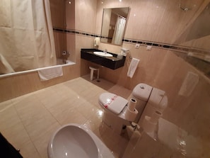 Un baño con bañera, inodoro, lavabo y espejo.