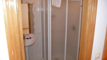 Un baño con cabina de ducha, lavamanos y espejo.