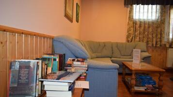 A living room with a sofa, a coffee table, and a stack of books.