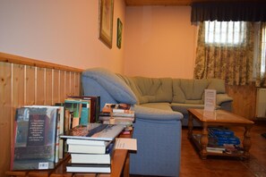 A living room with a sofa, a coffee table, and a stack of books.