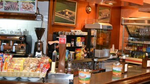 Interior de un restaurante que muestra una máquina de café, una caja registradora y diversos productos alimenticios.