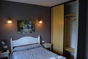 A bedroom with a bed, nightstands, a painting of a waterfall, and a wardrobe.