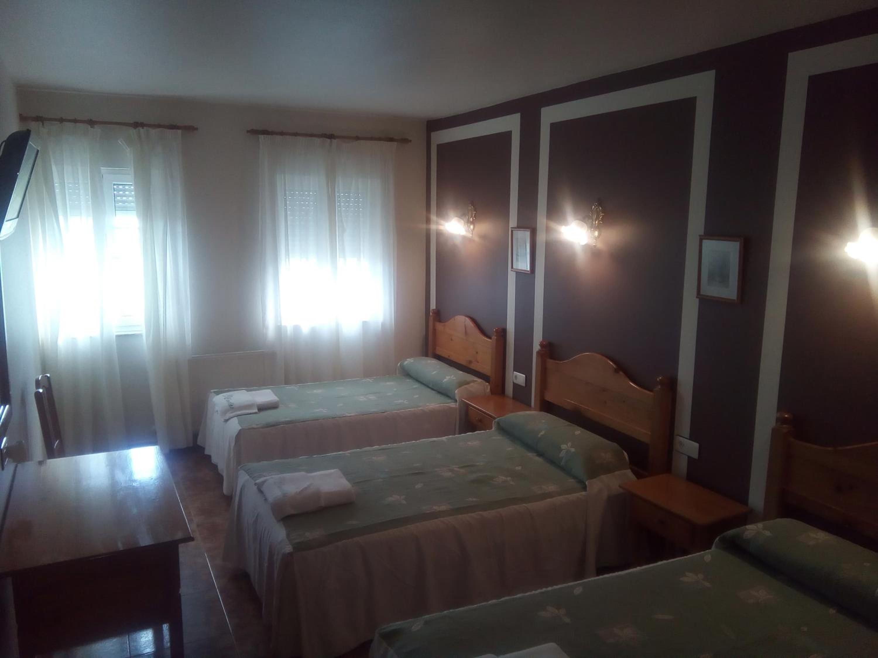 Una habitación de hotel con dos camas individuales, un escritorio de madera y una silla.