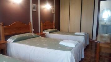A hotel room with two single beds, a wooden headboard, a bedside table, and a large window.